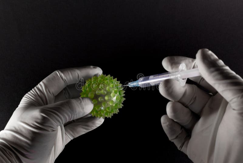 Two latex clad hands injecting a hypodermic syringe into a large green virus on black background. Two latex clad hands injecting a hypodermic syringe into a large green virus on black background