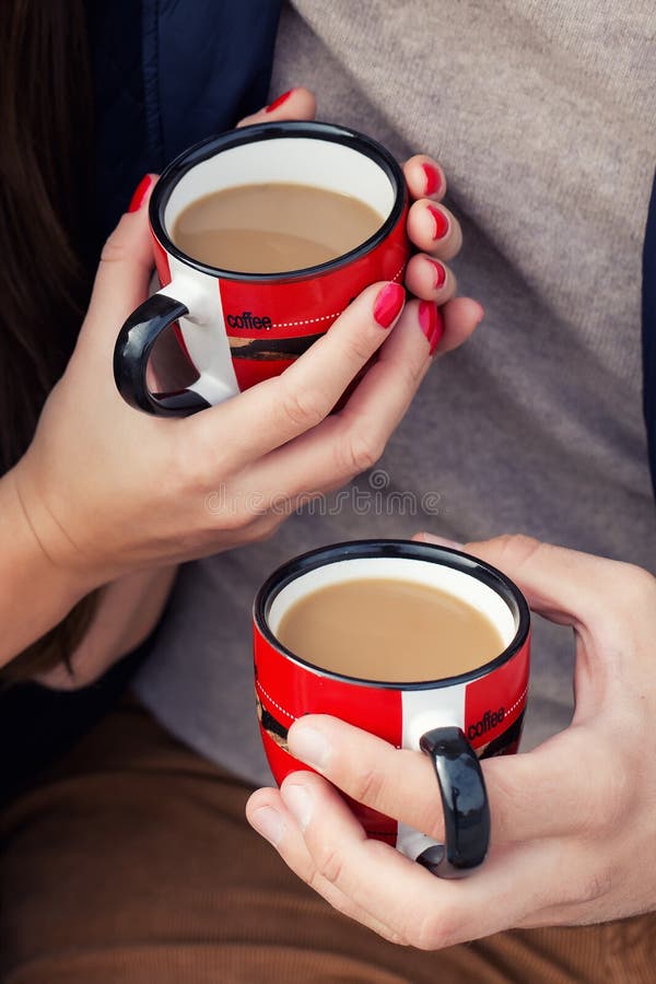 Mãos com as xícaras de café de um par com leite imagem de stock royalty free