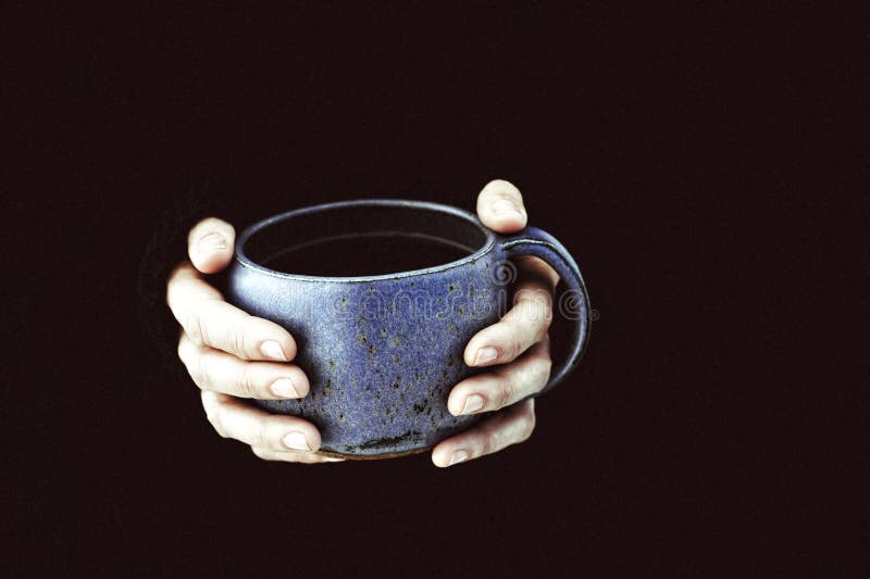 Mãos da mulher que guardam um grande copo de chá