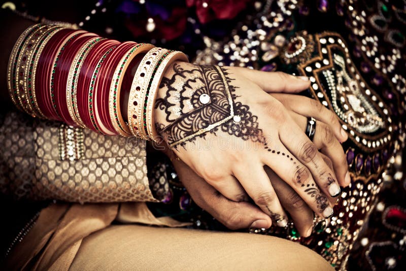 East Indian wedding couple holding hands with traditional jewelry, henna and dress. East Indian wedding couple holding hands with traditional jewelry, henna and dress