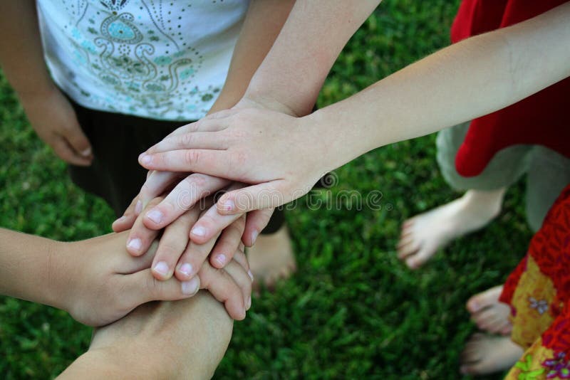 Children standing in a circle with hands on top of each other. Children standing in a circle with hands on top of each other.