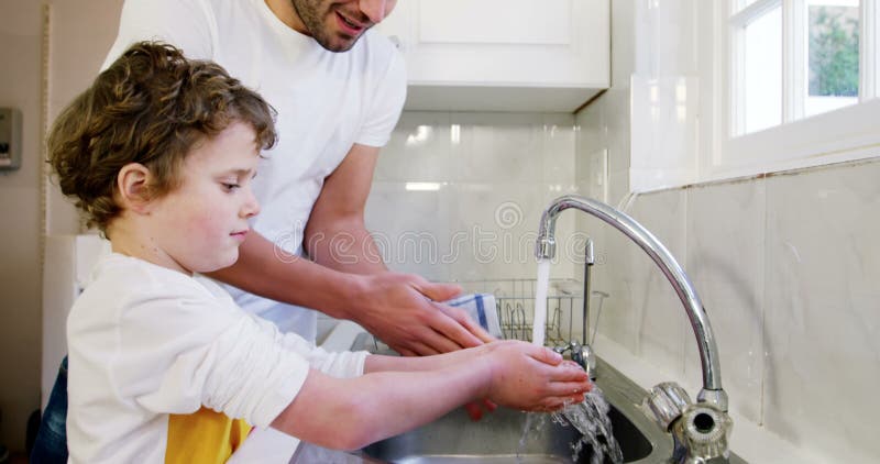 Mãos de lavagem do pai e do filho na banca da cozinha