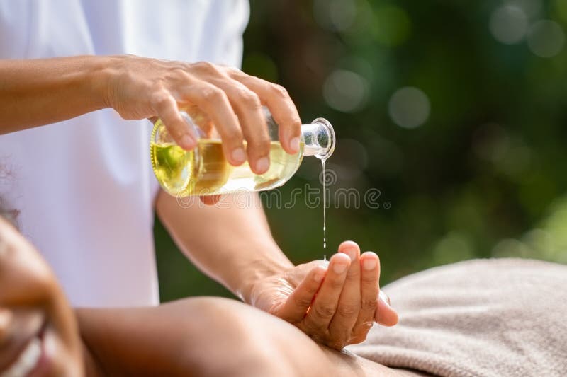 Closeup of masseuse hands pouring aroma oil on women back. Woman prepare to do oriental spa massage for relaxing treatment. Therapist doing aromatherapy oil massage on girl body. Body care concept. Closeup of masseuse hands pouring aroma oil on women back. Woman prepare to do oriental spa massage for relaxing treatment. Therapist doing aromatherapy oil massage on girl body. Body care concept