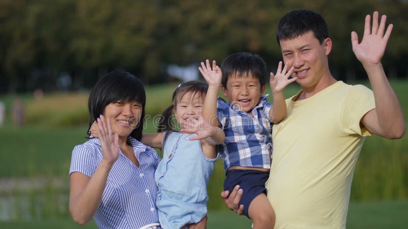 Mãos de ondulação da família asiática feliz junto fora