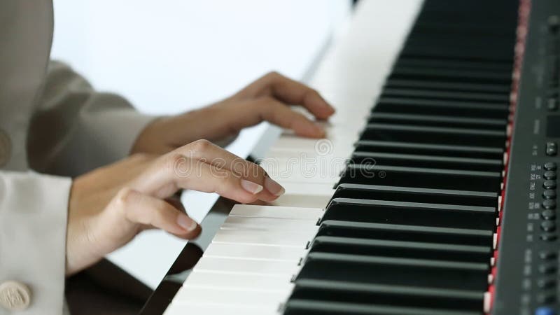 Mãos de uma jovem mulher que joga o piano