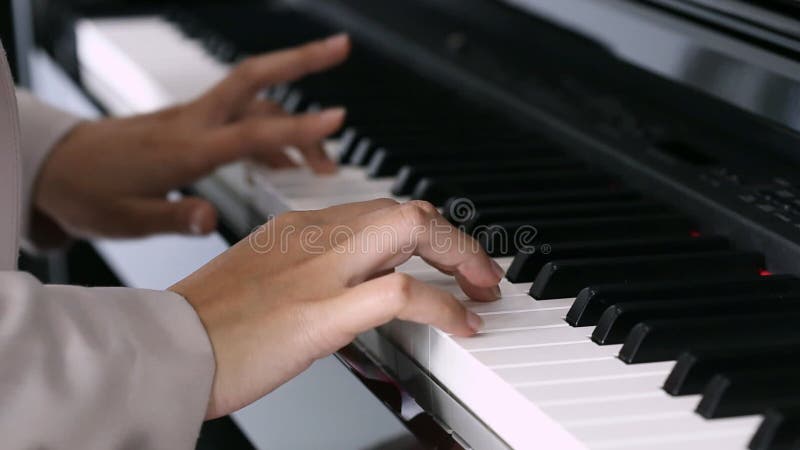 Mãos de uma jovem mulher que joga o piano