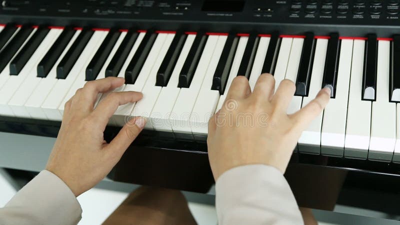 Mãos de uma jovem mulher que joga o piano