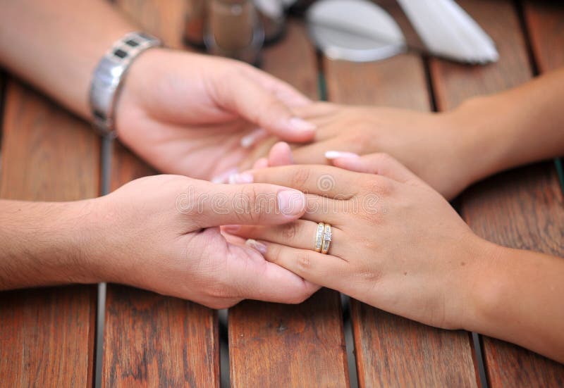 A married couple holding their hands on a table - valentines day. A married couple holding their hands on a table - valentines day