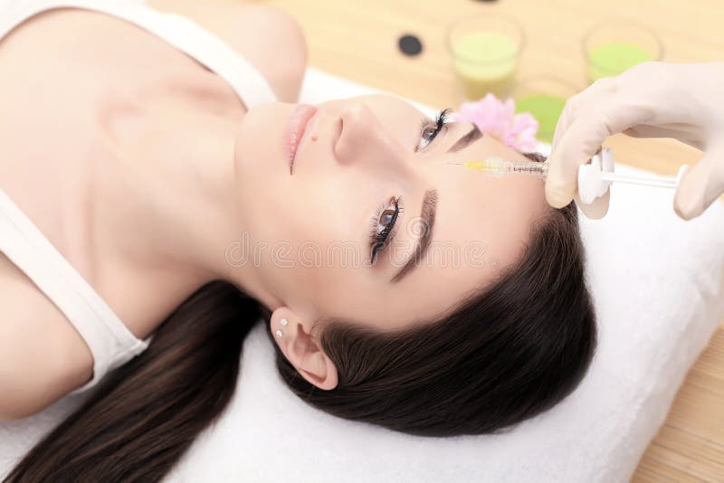 Mãos do cosmetologist que fazem a injeção na cara A jovem mulher obtém a beleza injeções faciais no salão de beleza Envelheciment imagem de stock Mãos do cosmetologist que fazem a injeção na cara A jovem mulher obtém a beleza injeções faciais no salão de beleza Envelheciment imagem de stock