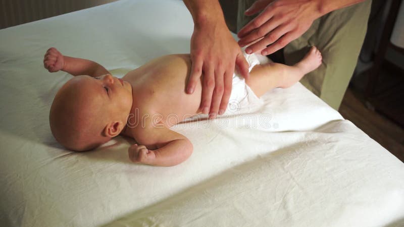 Mãos do massagista profissional esfregar cuidadosamente o estômago infantil pequeno