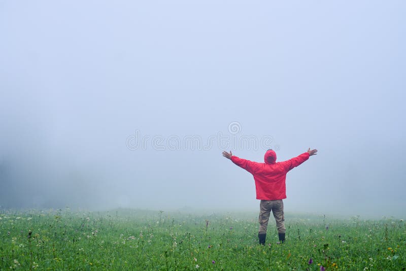 Rear view of male hiker with outstretched hands in foggy weather. Rear view of male hiker with outstretched hands in foggy weather