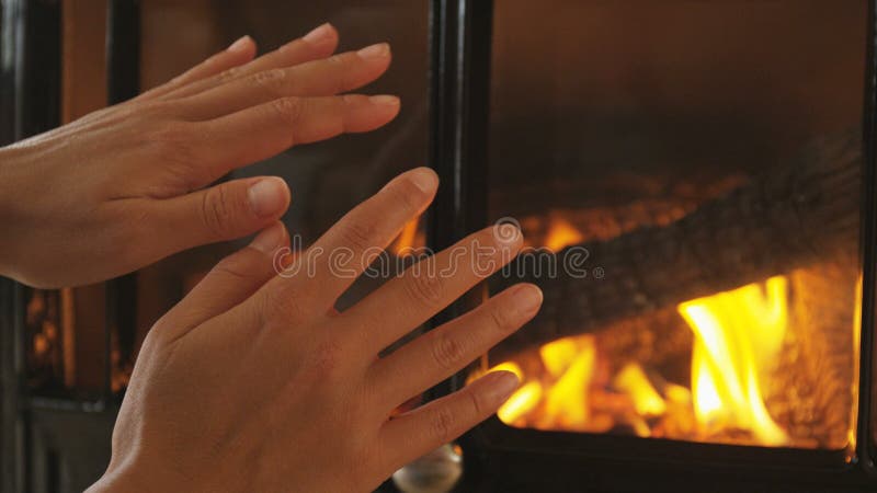 Mãos frias mulheres esfregando as mãos pela lareira aquecendo e aconchegando no inverno