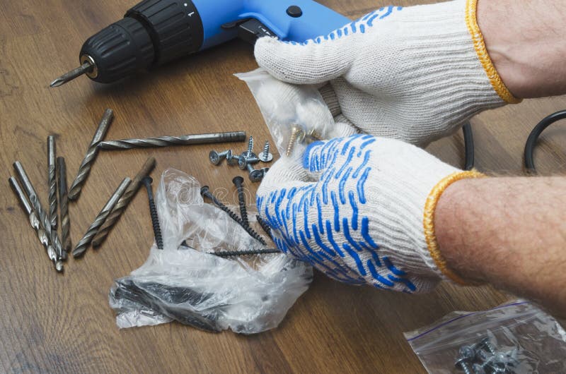 Mãos masculinas nas luvas que escolhem os parafusos para a chave de fenda Conceito da renovação na casa imagens de stock Mãos masculinas nas luvas que escolhem os parafusos para a chave de fenda Conceito da renovação na casa imagens de stock
