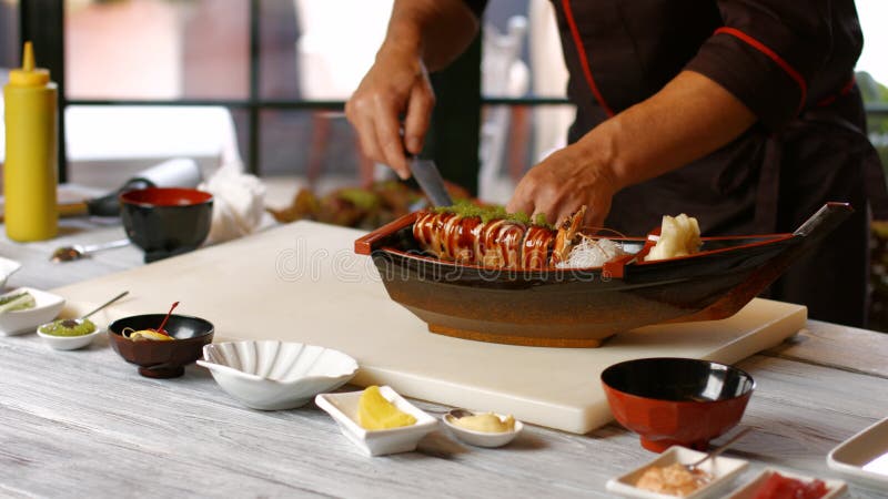 Mãos masculinas que fazem o barco do sushi