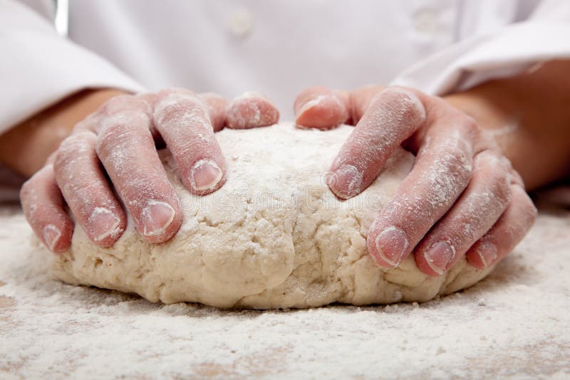 Mãos que amassam a massa de pão de pão