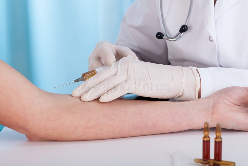 Mãos que dão a injeção da vacinação