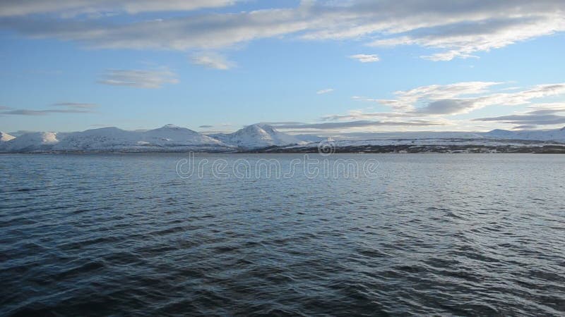 Mächtige Ansicht der hohen See mit funkelnder Sonnenreflexion auf Fjordoberfläche mit mächtigem schneebedecktem Gebirgszug und Be