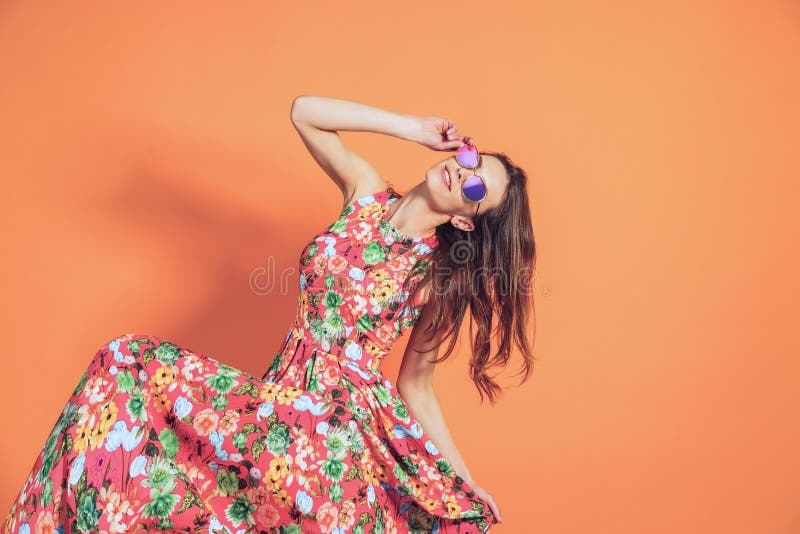 Girl in floral dress emotionally poses on the orange background. Girl in floral dress emotionally poses on the orange background.
