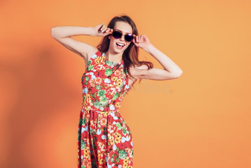 Girl in floral dress emotionally poses on the orange background. Girl in floral dress emotionally poses on the orange background.