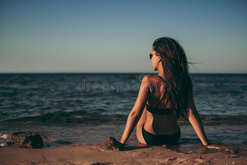 Mädchen, das auf dem Strand sitzt und zur Seite schaut lizenzfreie stockfotografie Mädchen, das auf dem Strand sitzt und zur Seite schaut lizenzfreie stockfotografie