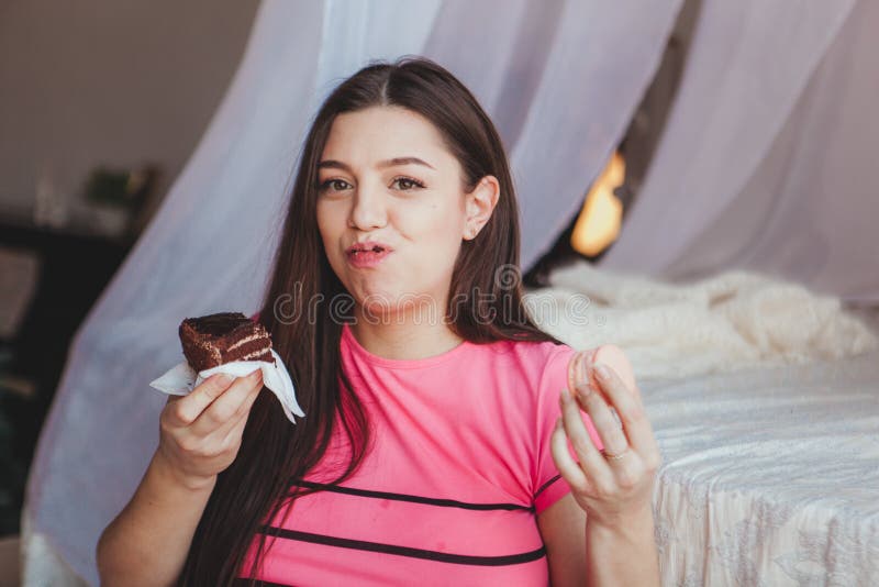 Mädchen, das geschmackvollen browny Kuchen mit in Schlafzimmer isst Süßer Nachtisch Guten Morgen lizenzfreie stockfotos Mädchen, das geschmackvollen browny Kuchen mit in Schlafzimmer isst Süßer Nachtisch Guten Morgen lizenzfreie stockfotos