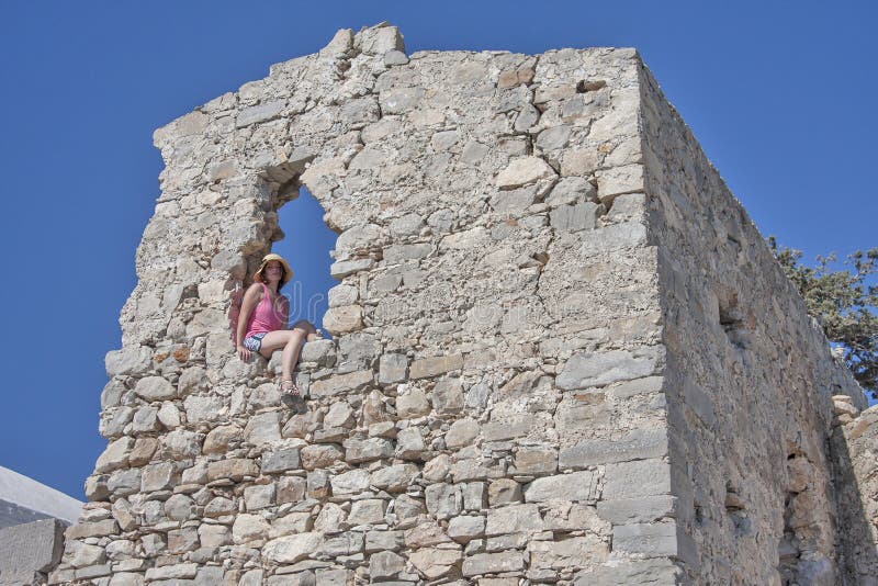 Mädchen, das innerhalb einer alten Mauer sitzt stockbild