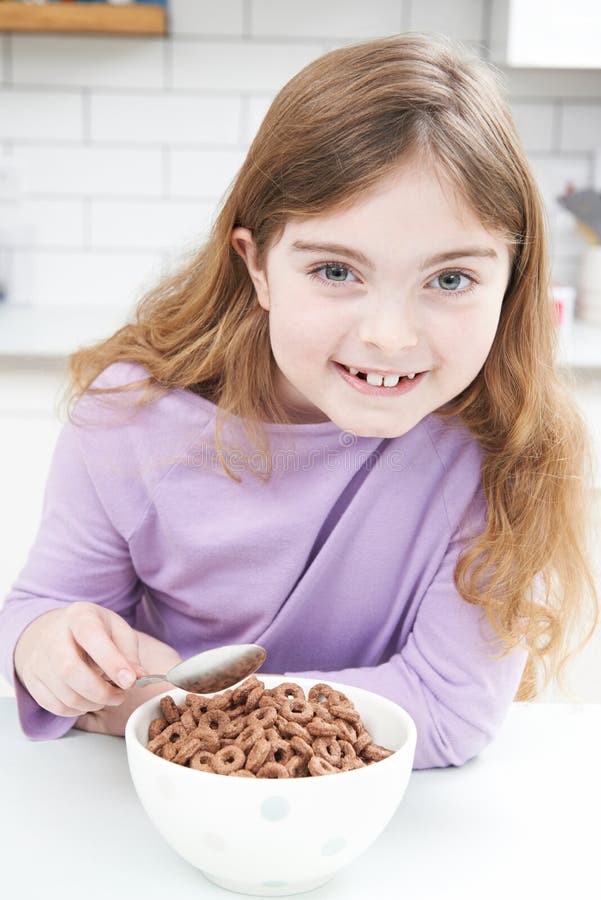 Mädchen, das Schüssel zuckerhaltige Frühstückskost aus Getreide in der Küche isst lizenzfreies stockbild Mädchen, das Schüssel zuckerhaltige Frühstückskost aus Getreide in der Küche isst lizenzfreies stockbild