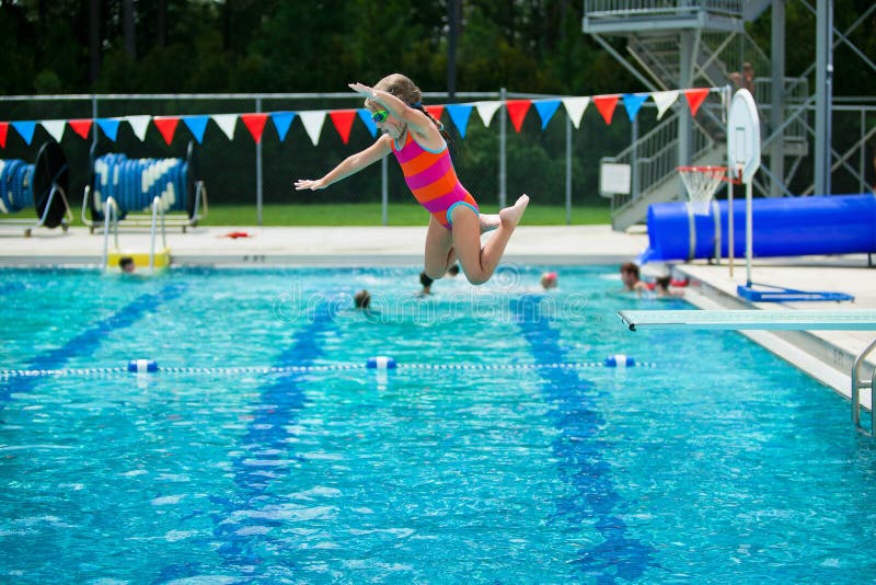 Mädchen, das vom Sprungbrett während ihrer Schwimmenlektionen am lokalen Pool im Freien im Sommer springt