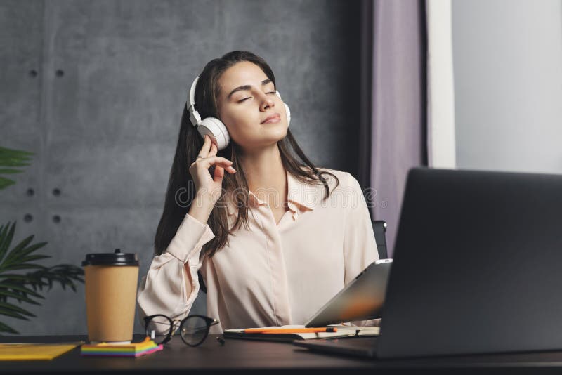 Girl in headphones enjoying music in front of laptop. Great sound quality and design of wireless earphones. Female streaming relaxing music and entertainment content from internet. Digital mobile apps. Girl in headphones enjoying music in front of laptop. Great sound quality and design of wireless earphones. Female streaming relaxing music and entertainment content from internet. Digital mobile apps