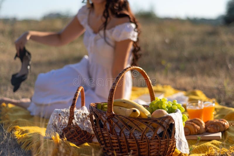 Mädchen in einem Hut und in einem weißen Kleid, die auf einem Picknick in einer Rasenfläche in defocus verschwommener Fleck sitze lizenzfreies stockbild