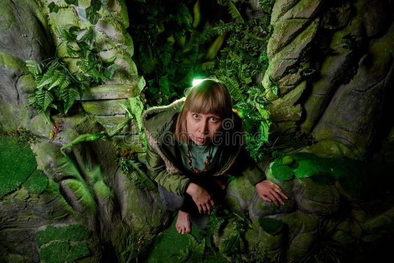 Mädchen in einer grünen Jacke mit dem blonden Haar nahe einem künstlichen Felsen mit einer Grotte Fabelhafte Fotoaufnahme im Stud lizenzfreie stockfotos Mädchen in einer grünen Jacke mit dem blonden Haar nahe einem künstlichen Felsen mit einer Grotte Fabelhafte Fotoaufnahme im Stud lizenzfreie stockfotos