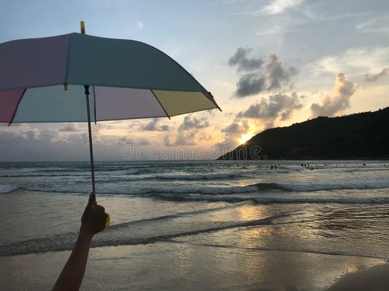 Mädchen hält einen bunten Pastellregenschirm auf dem Strand mit überraschendem Sonnenuntergang stockbild Mädchen hält einen bunten Pastellregenschirm auf dem Strand mit überraschendem Sonnenuntergang stockbild