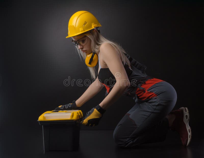 Mädchen im Overall, der einen Koffer mit Arbeitsgeräten hält stockbilder