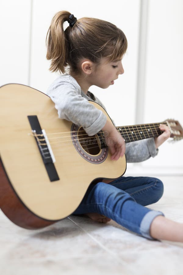 Mädchen mit 9-Jährigen, das lernt, die Gitarre zu spielen lizenzfreies stockbild Mädchen mit 9-Jährigen, das lernt, die Gitarre zu spielen lizenzfreies stockbild