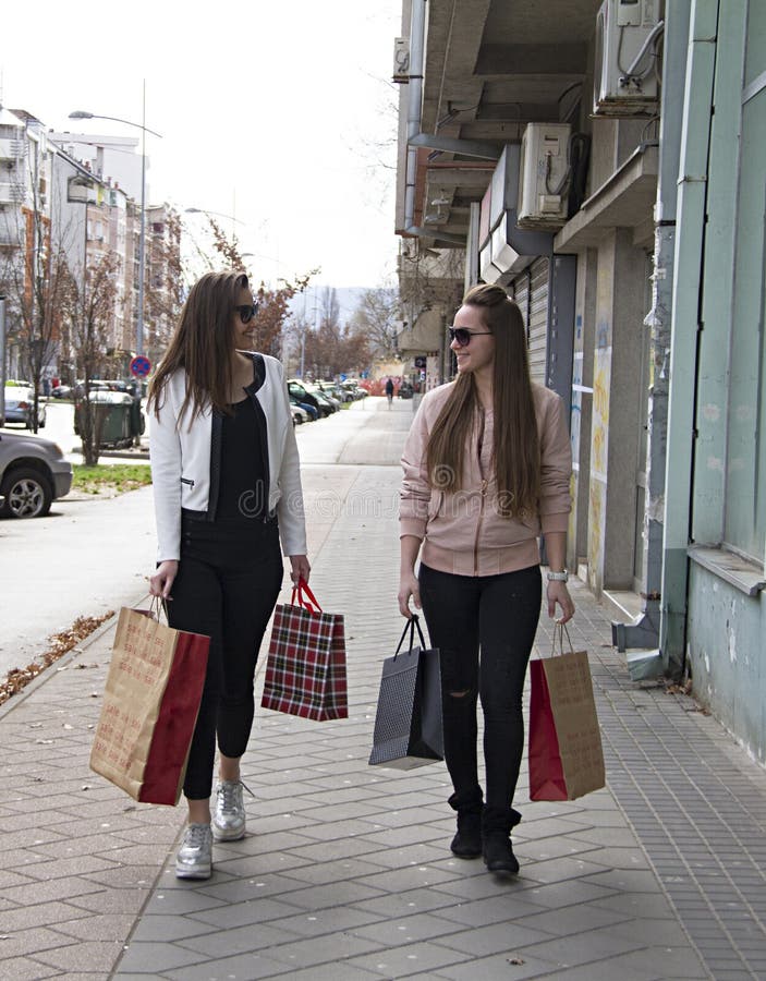 Mädchen sind lächelndes Hinuntergehen die Straße, nachdem sie Kleidung gekauft haben und Schuhe stockbilder Mädchen sind lächelndes Hinuntergehen die Straße, nachdem sie Kleidung gekauft haben und Schuhe stockbilder