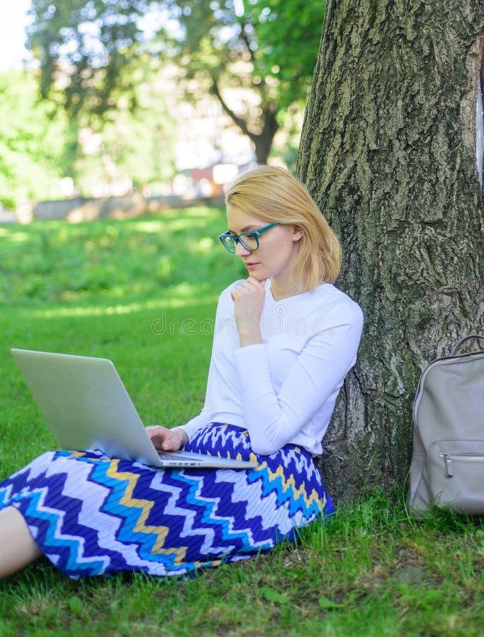 Girl sit grass lean tree trunk with notebook. Wi fi network connection free access. Surfing internet in nature. Woman with laptop works outdoor, park background. Lady freelancer working in park. Girl sit grass lean tree trunk with notebook. Wi fi network connection free access. Surfing internet in nature. Woman with laptop works outdoor, park background. Lady freelancer working in park.