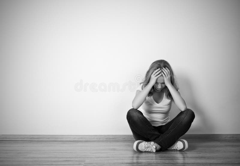 Mädchen sitzt in einer Krise auf dem Boden nahe der Wand