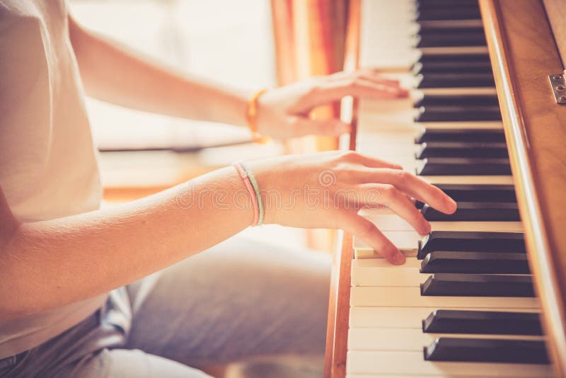 Mädchen spielt Klavier zu Hause, hohe Winkelsicht, undeutlicher Hintergrund. Junges Mädchen übt Klavier zu Hause Ausschnitt des Klavier- und Handinstrumentes, das den Ausbildungsmusikalischen Sonnenlichtlebensstil der musikschlüsselkindheit ausübt Frauen-Jugendpraxis des weiblichen Personeninnenberufungshobbyleistung der Tag einer Pianistmusikermelodienfreizeittageslichts begabten Kindersitzende spielt, lernen der symphonischen undeutliches Kind Finger-Lektion des Fähigkeitsausbildungsstudenten