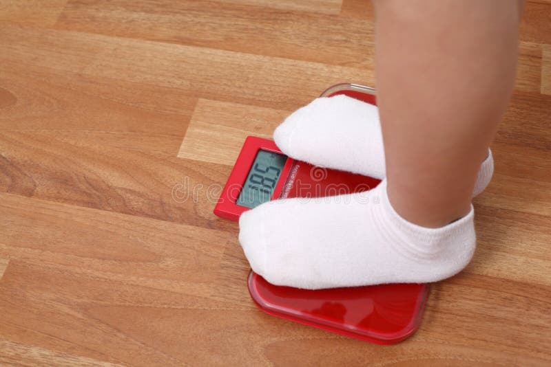 Girl stands on the weights. feet in white socks on the scales. Girl stands on the weights. feet in white socks on the scales