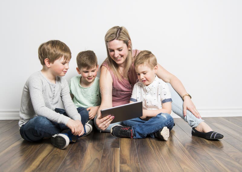 Mädchen und ihre Mutter sitzen auf dem Boden, unter Verwendung einer digitalen Tablette stockfoto