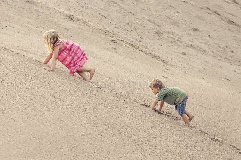 Mädchen und Junge, die auf der Sanddüne klettern Baum auf dem Gebiet lizenzfreie stockfotografie Mädchen und Junge, die auf der Sanddüne klettern Baum auf dem Gebiet lizenzfreie stockfotografie