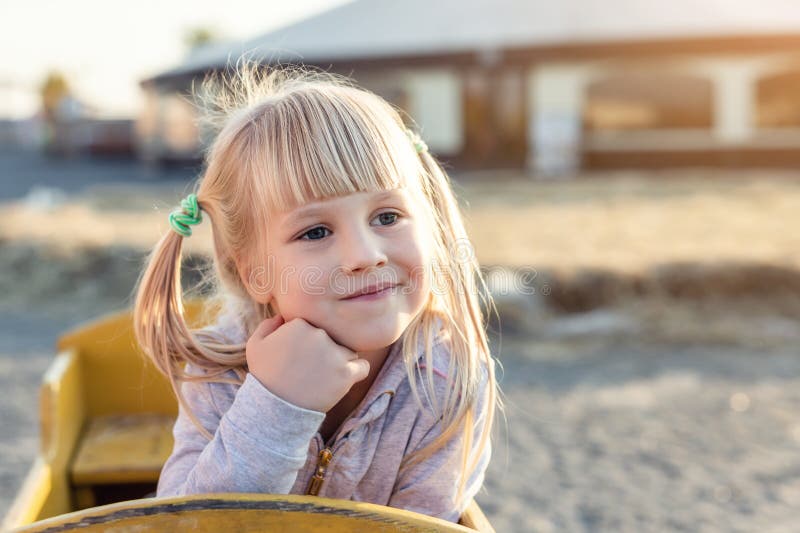 Mädchenporträt des entzückenden netten Kaukasiers blondes Kinder, dasim hölzernen Wagen sitzt, beiseite schaut und am Bauernhof o lizenzfreie stockfotografie Mädchenporträt des entzückenden netten Kaukasiers blondes Kinder, dasim hölzernen Wagen sitzt, beiseite schaut und am Bauernhof o lizenzfreie stockfotografie