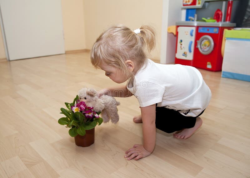 Mädchenspiele mit Blumen- und Spielzeughund lizenzfreies stockfoto Mädchenspiele mit Blumen- und Spielzeughund lizenzfreies stockfoto