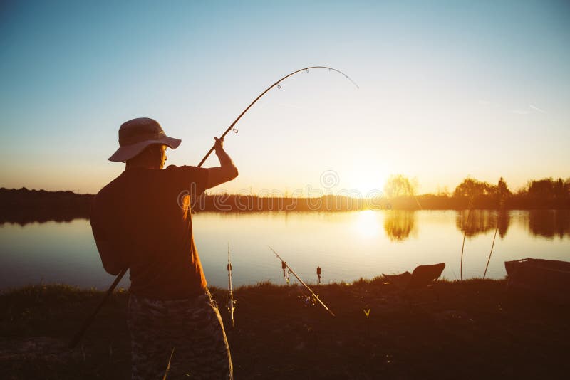Män som fiskar i solnedgång och kopplar av, medan tycka om hobby arkivbild Män som fiskar i solnedgång och kopplar av, medan tycka om hobby arkivbild