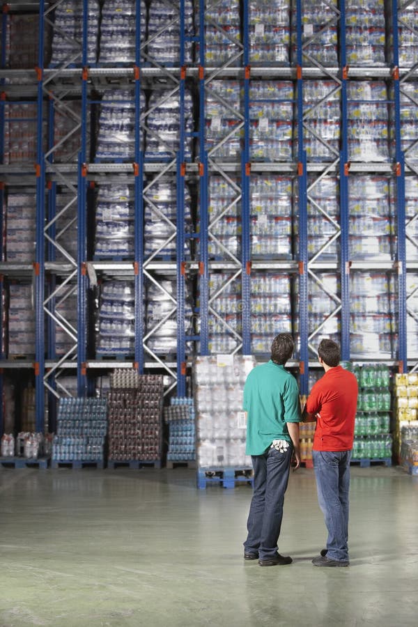 Männer, die volle Lager-Regale betrachten lizenzfreie stockbilder Männer, die volle Lager-Regale betrachten lizenzfreie stockbilder