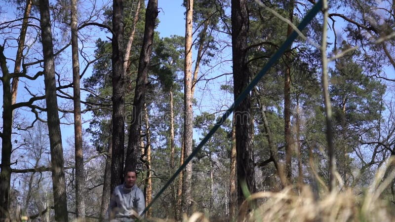 Människan som hoppar och gör trick på slackline i skogen i långsam rörelse stock video