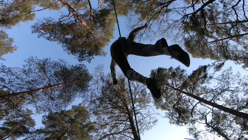 Människan som hoppar och gör trick på slackline i skogen i långsam rörelse arkivfilmer