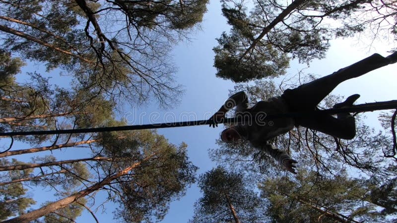 Människan som hoppar och gör trick på slackline i skogen i långsam rörelse arkivfilmer