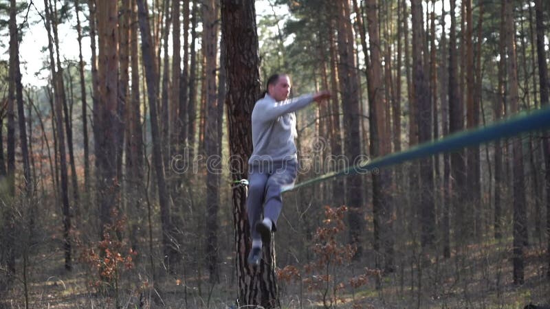 Människan som hoppar och gör trick på slackline i skogen i långsam rörelse arkivfilmer