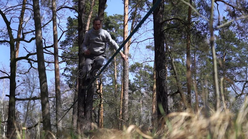 Människan som hoppar och gör trick på slackline i skogen i långsam rörelse arkivfilmer